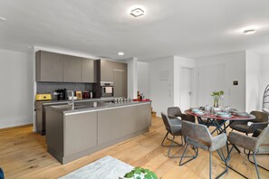 Una cocina moderna con armarios grises, una isla central y un comedor con sillas y una mesa.