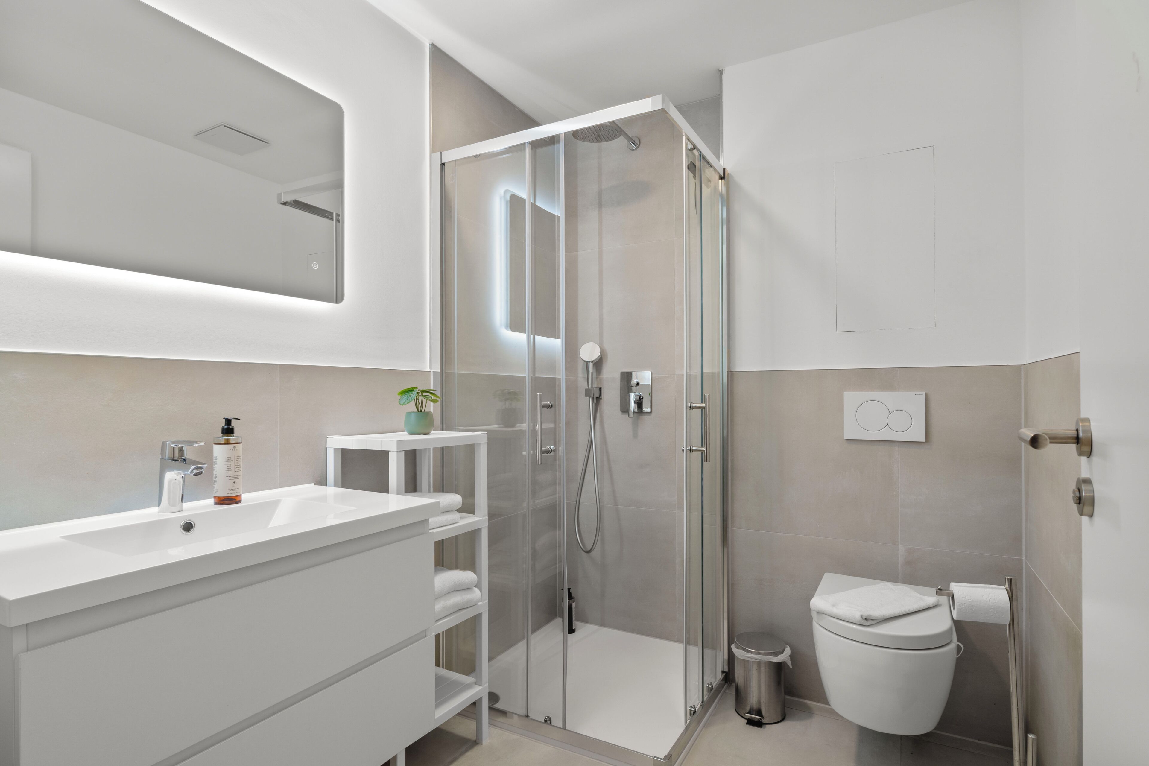 Une salle de bain moderne avec une douche à parois de verre, un lavabo blanc et des toilettes.