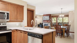A kitchen with wooden cabinets, a dishwasher, a microwave, and a dining area with a table and chairs.