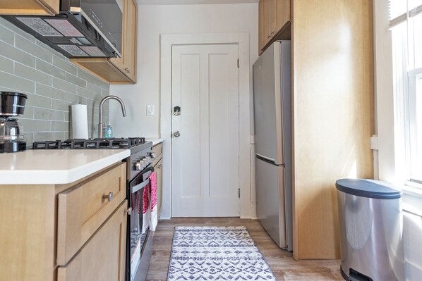 A compact kitchen with a gas stove, oven, and stainless steel refrigerator. - Colorful Modern Hideaway In Downtown Woodstock - AC & WiFi (Woodstock)