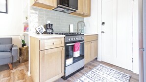 A compact kitchen with wooden cabinets, a stainless steel oven, and a microwave. - Colorful Modern Hideaway In Downtown Woodstock - AC & WiFi (Woodstock)