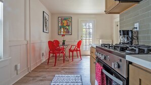A kitchen with a gas stove, oven, and a dining area with red chairs. - Colorful Modern Hideaway In Downtown Woodstock - AC & WiFi (Woodstock)