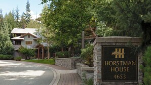 A sign for Horstman House with the number 4653, surrounded by lush greenery and a house in the background.