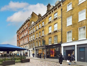 A row of traditional brick buildings with multiple stories, featuring large windows and a mix of storefronts and residential units. - Be London - The Covent Garden Residences (London)