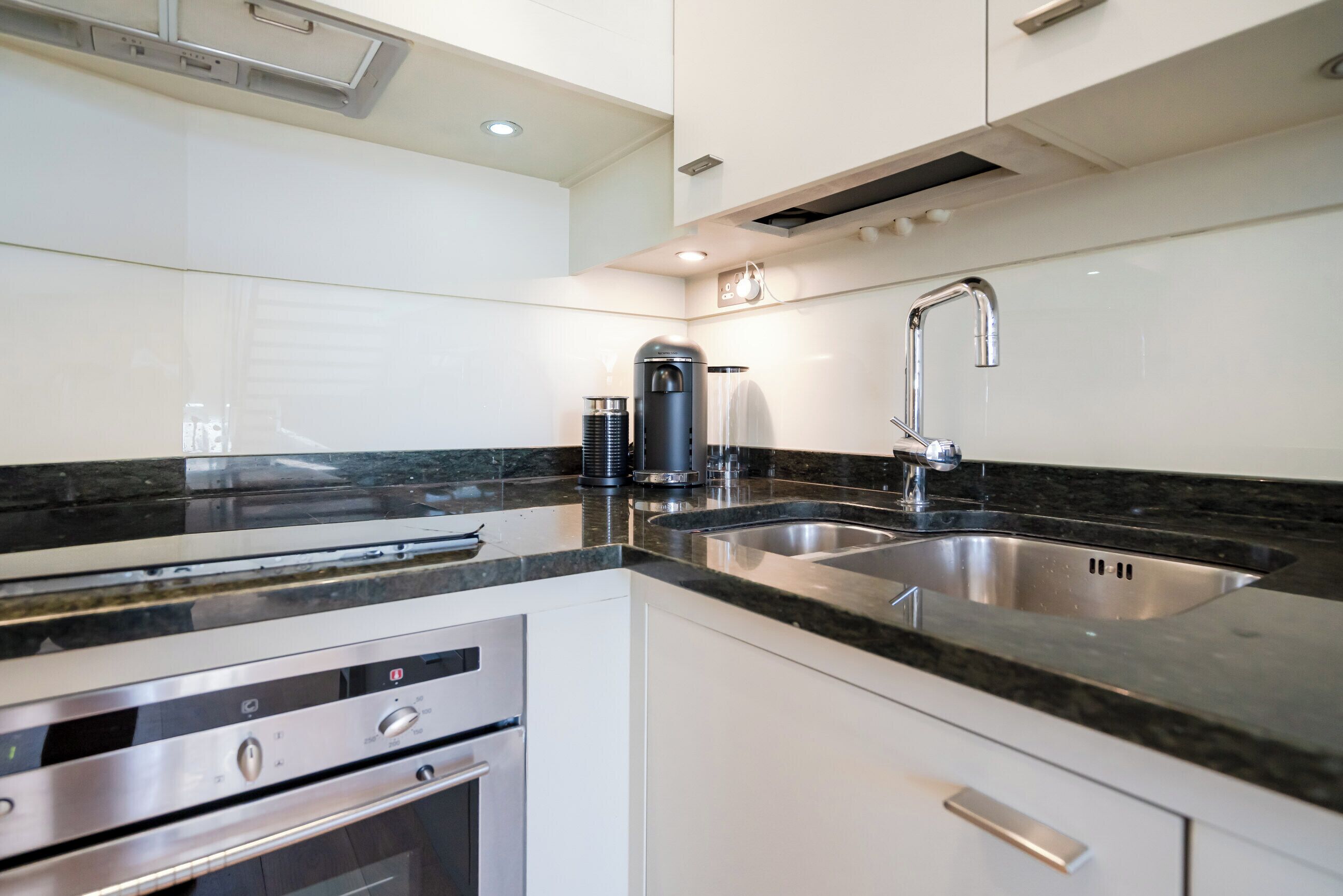 A modern kitchen with stainless steel appliances, a double sink, and a black granite countertop.