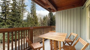 Eine Holzterrasse mit Tisch und Stühlen, umgeben von Bäumen.