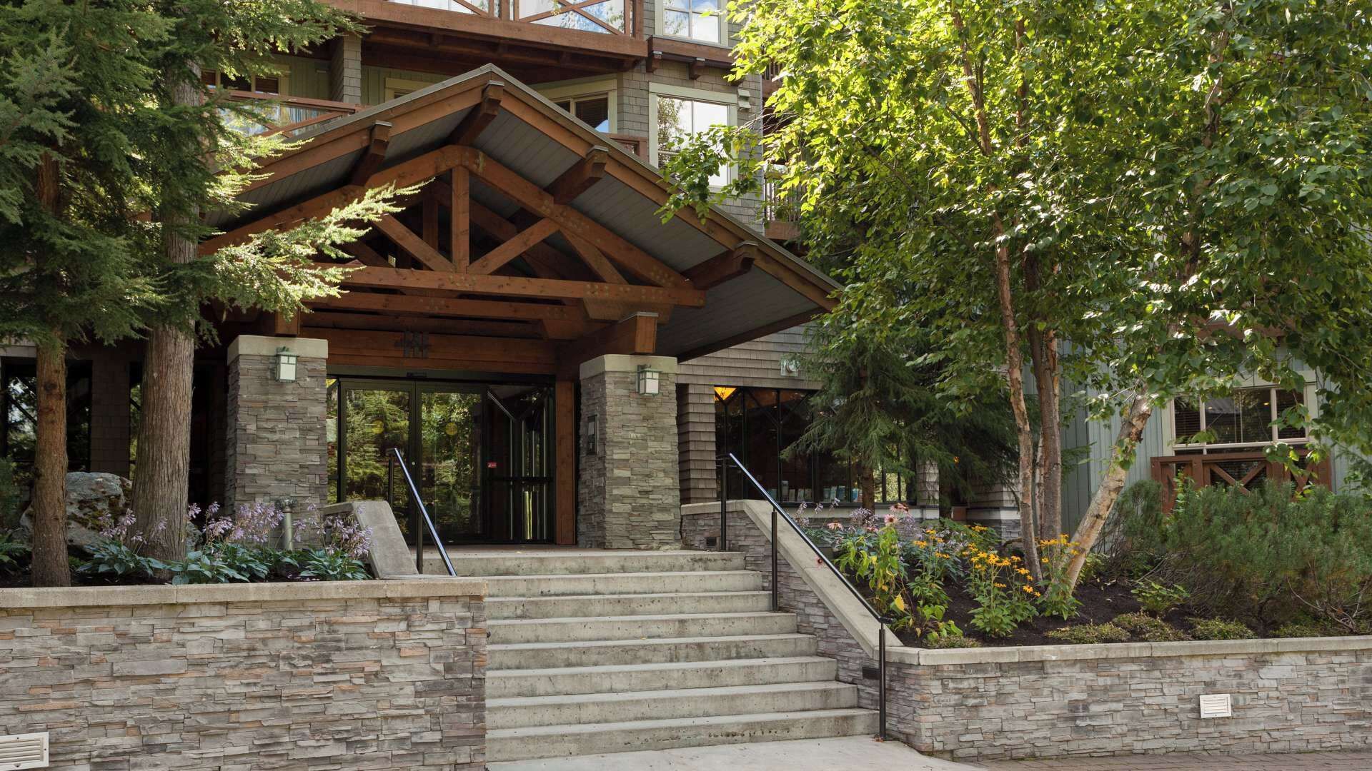 A building with a stone facade, wooden beams, and a staircase leading to a covered entrance.
