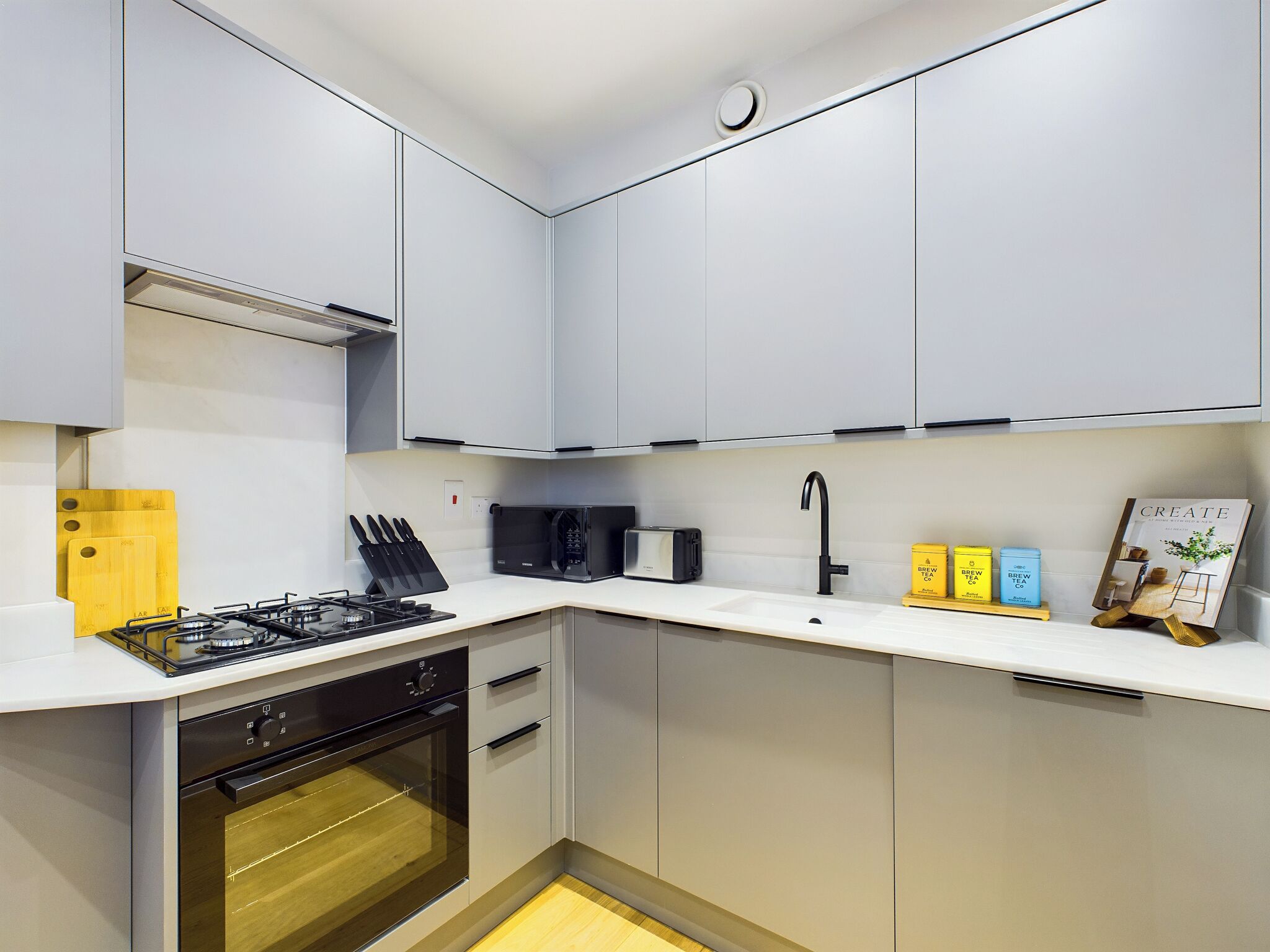 A modern kitchen with white cabinets, a gas stove, an oven, and a microwave.