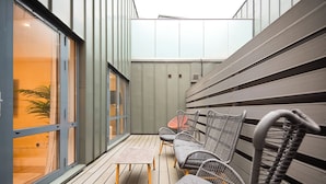 Un'area relax esterna moderna con mobili in vimini e un pavimento in legno.