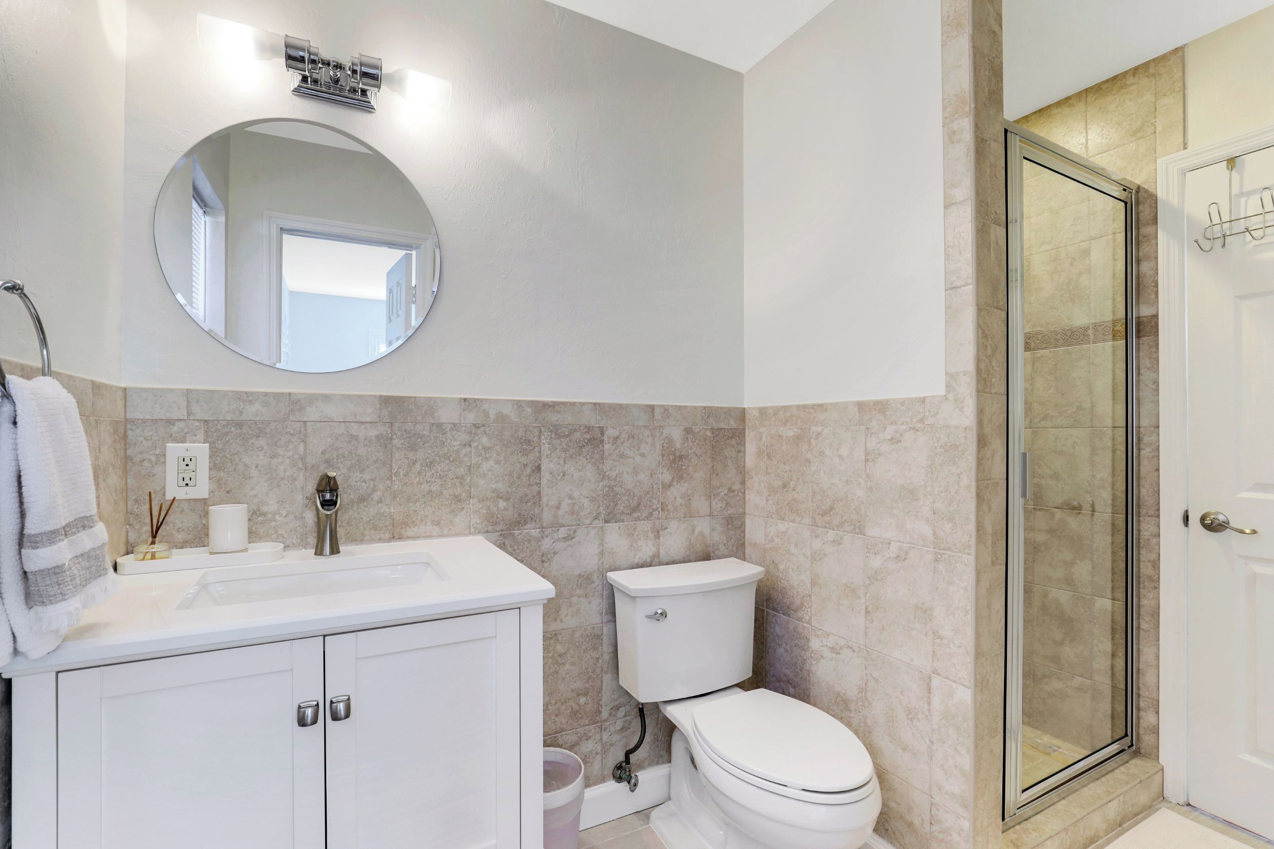 A bathroom with a white sink, mirror, toilet, and glass shower enclosure.