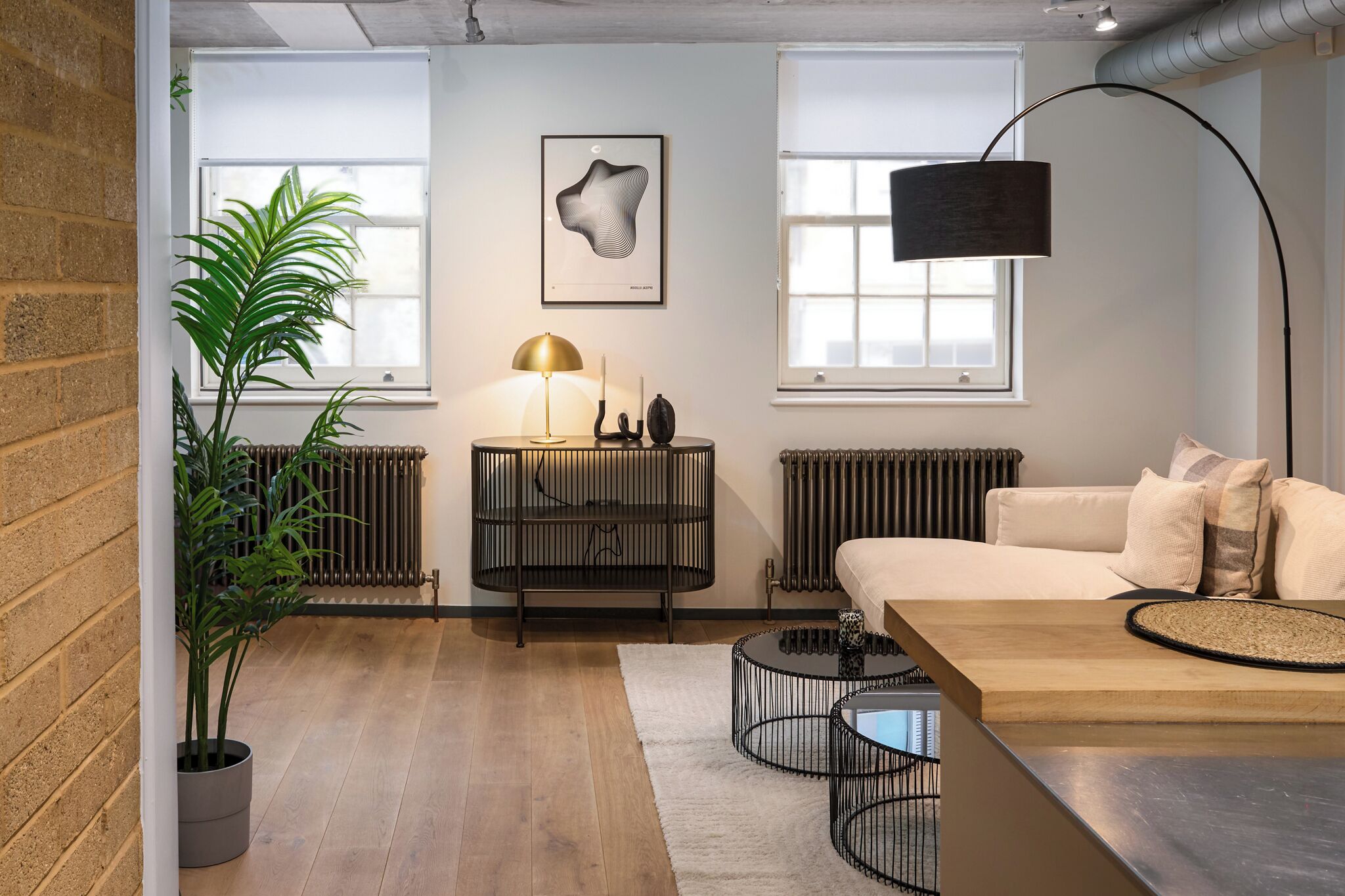 A modern living room with a sofa, a coffee table, a floor lamp, a radiator, and a potted plant.