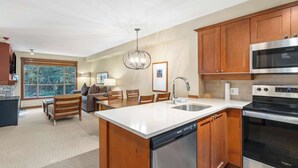 Una cocina moderna con armarios de madera, un microondas de acero inoxidable, lavavajillas integrado y una isla grande con un fregadero.