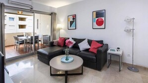 A modern living room with a black sofa, a round coffee table, and two abstract paintings on the wall. - Estepona Marina Apartment, Costa Del Sol (Estepona)
