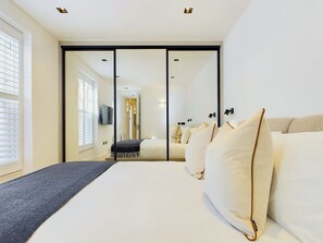 A modern hotel room with a large bed, a sliding door closet, and a view of the hallway.