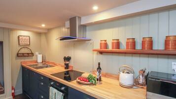 Una cocina moderna con encimera de madera, horno empotrado, hervidor y cafetera.