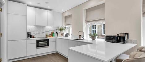 A modern kitchen with white cabinetry, a marble backsplash, and a large island with a sink and toaster.
