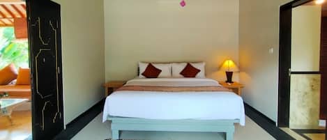 A bedroom with a bed, bedside lamp, and a view of the outside.