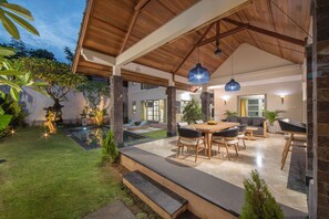 Une vaste terrasse dotée d’une piscine, d’un espace salon extérieur et d’une structure de plafond en bois.