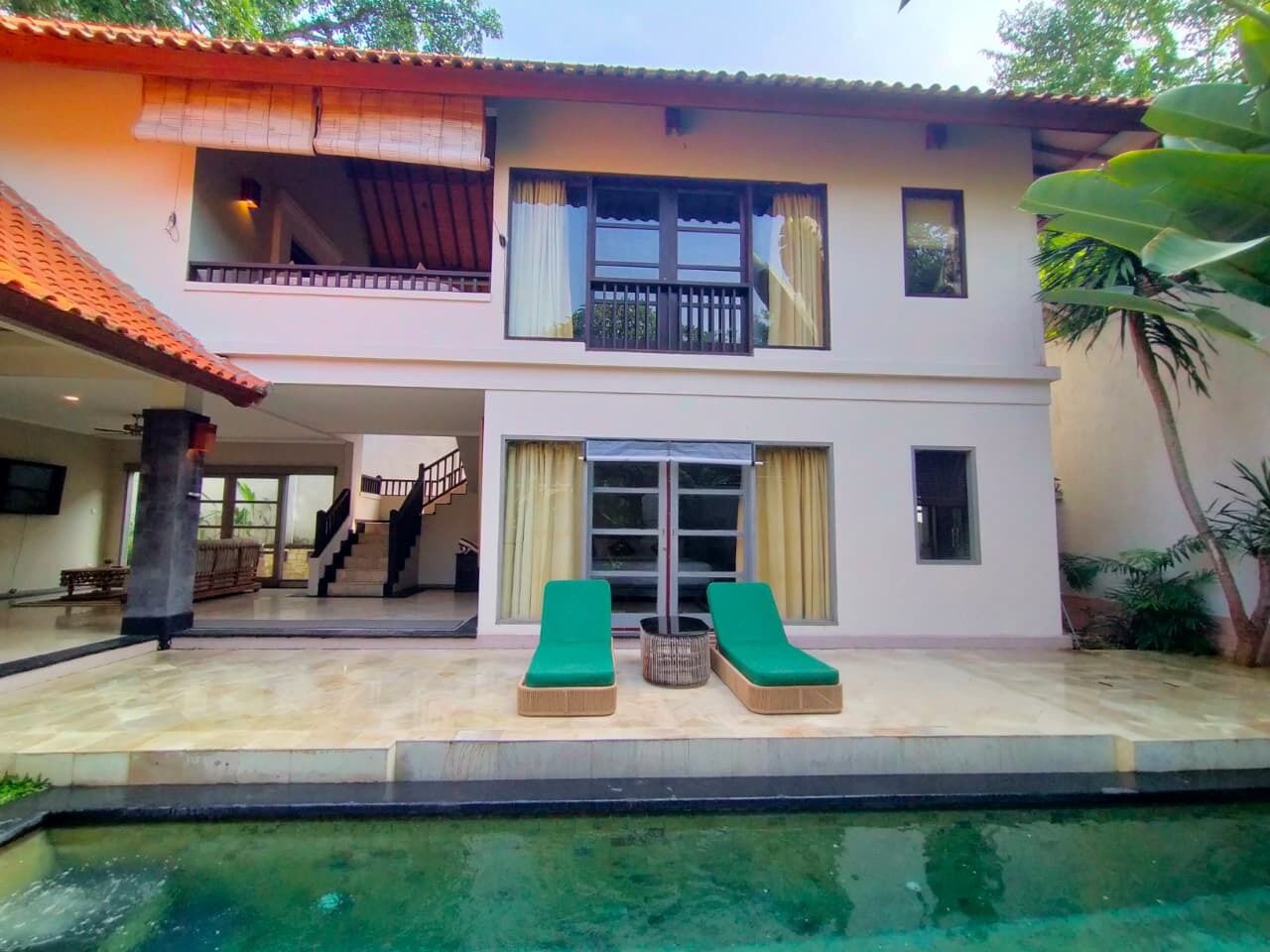 Une maison à deux étages dotée d’une piscine, d’un balcon et d’un escalier menant à l’étage supérieur.
