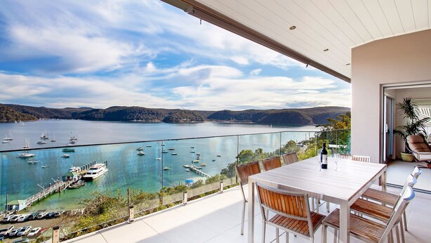 A balcony with a table and chairs overlooking a marina with boats and a lake. - The Commodore Penthouse (Palm Beach)