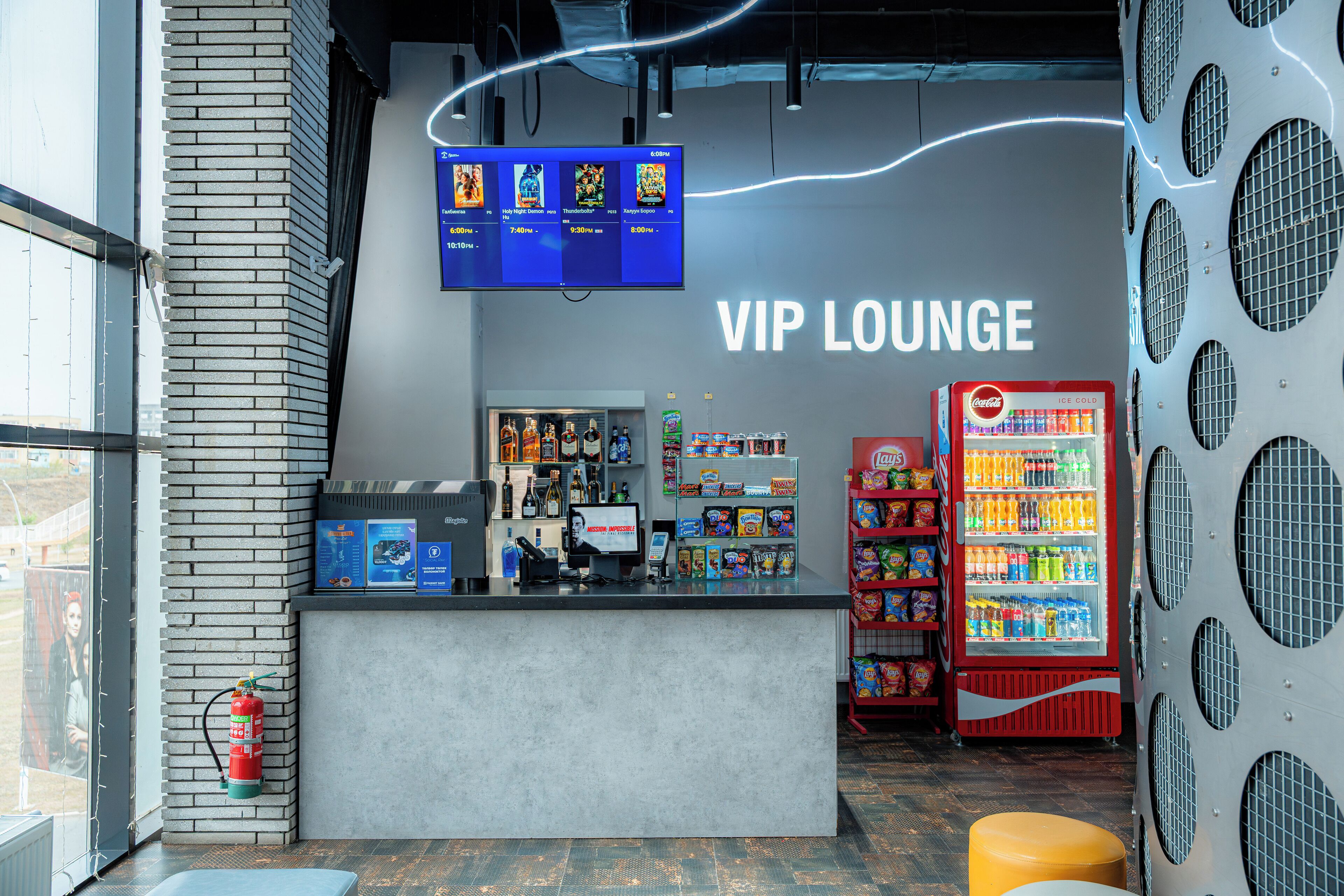 Eine VIP-Lounge mit einer Theke, einem Coca-Cola-Kühlschrank und einer Speisekarte.