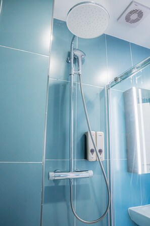 Eine Dusche mit Handbrause, einer fest installierten Bedienung und einem gläsernen Duschbereich.