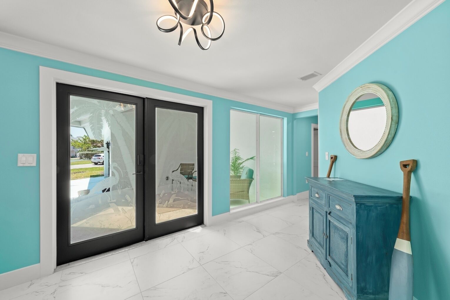 A spacious room with a sliding glass door leading to a patio, a blue cabinet, and a ceiling light fixture.