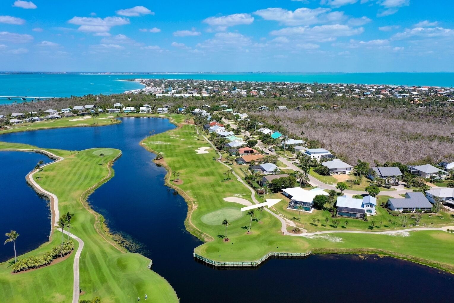 Ett flygbildsfoto av ett bostadsområde med hus, en golfbana och en stor sjö eller ett stort vattendrag.