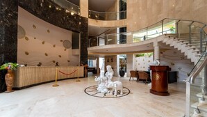 A spacious lobby with a marble floor, a reception desk, a statue of elephants, and a staircase. - GRANDEUR SANCHI RESORT (Calangute)