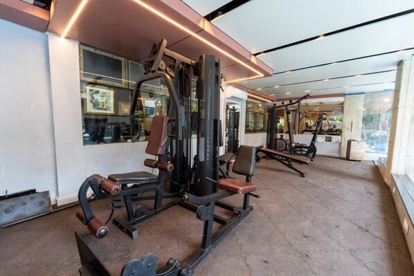 Ein Fitnessstudio mit Trainingsgeräten, großen Fenstern und einem Betonboden.