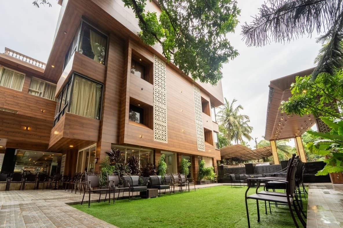 A modern building with a courtyard, outdoor seating, and lush greenery.