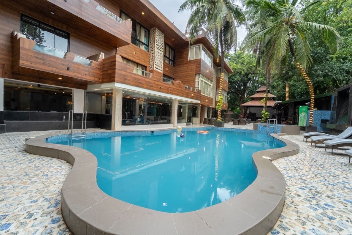 Ein modernes Gebäude mit Swimmingpool, Palmen und Liegestühlen.