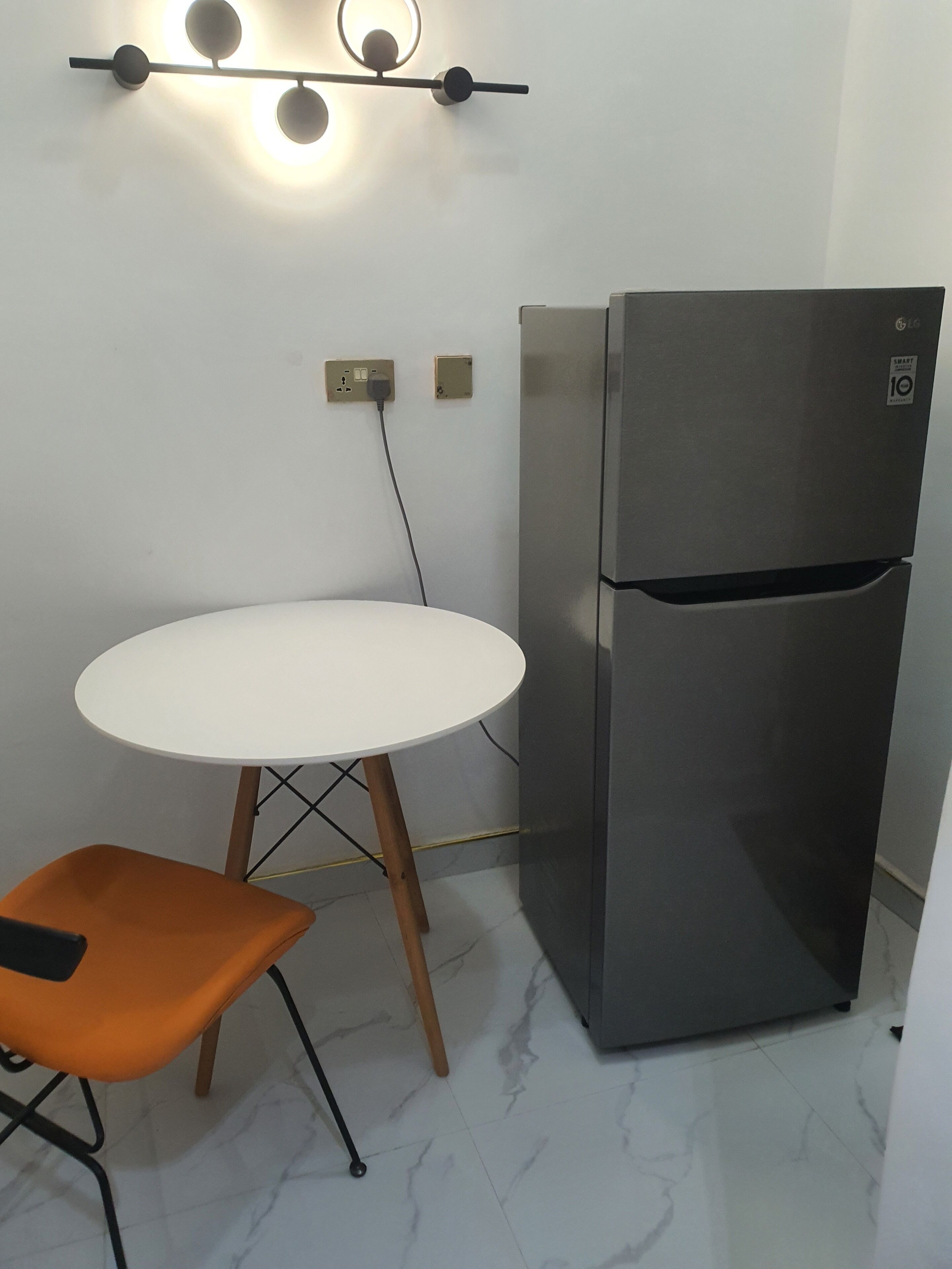 A compact kitchen with a white table and a modern stainless steel refrigerator.