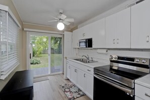 A kitchen with white cabinets, a built-in microwave, a stainless steel oven, and a sliding glass door leading to a backyard.