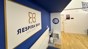 A modern bathroom with a blue accent wall, a large mirror, and a toilet.