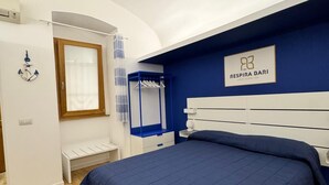 A bedroom with a large bed, a wardrobe, a mirror, and a hanging light fixture.