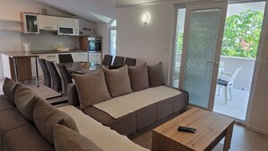 A modern living room with a sofa, coffee table, and dining area. - Apartments Ivankovic (Nin)