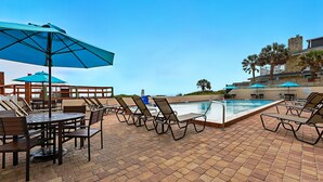 A poolside area with lounge chairs, umbrellas, and a pool. - Beacher's Lodge Studio Suite (not directly oceanfront) (Saint Augustine)