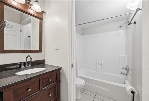 A bathroom with a sink, mirror, vanity, and a shower area.
