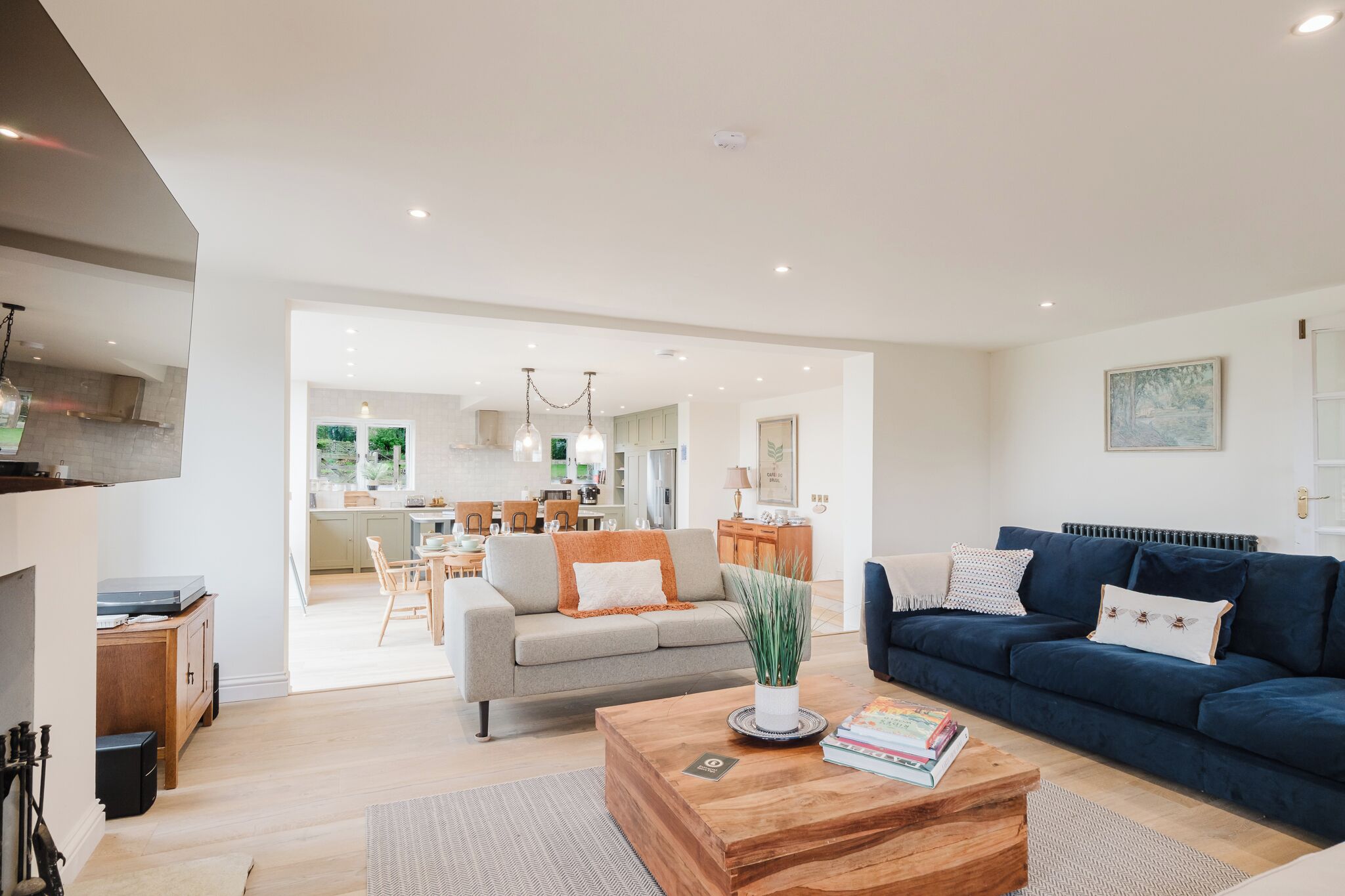 A modern living room with a sofa, coffee table, and a dining area in the background.