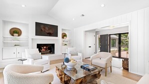 A modern living room with white furniture, a glass coffee table, and a fireplace. - 12 Woodbine Place: BESTNEST/Luxe, Private Pool, Stunning Golf View (Hilton Head Island)