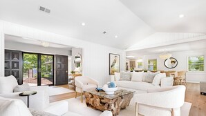 A spacious living room with a glass coffee table, white sofas, and a large window offering a view of the outdoors. - 12 Woodbine Place: BESTNEST/Luxe, Private Pool, Stunning Golf View (Hilton Head Island)