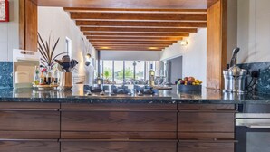 A modern kitchen with a wooden ceiling, a marble countertop, and a view to the outdoors.