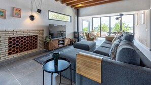 A modern living room with a fireplace, a large TV, and a sofa.