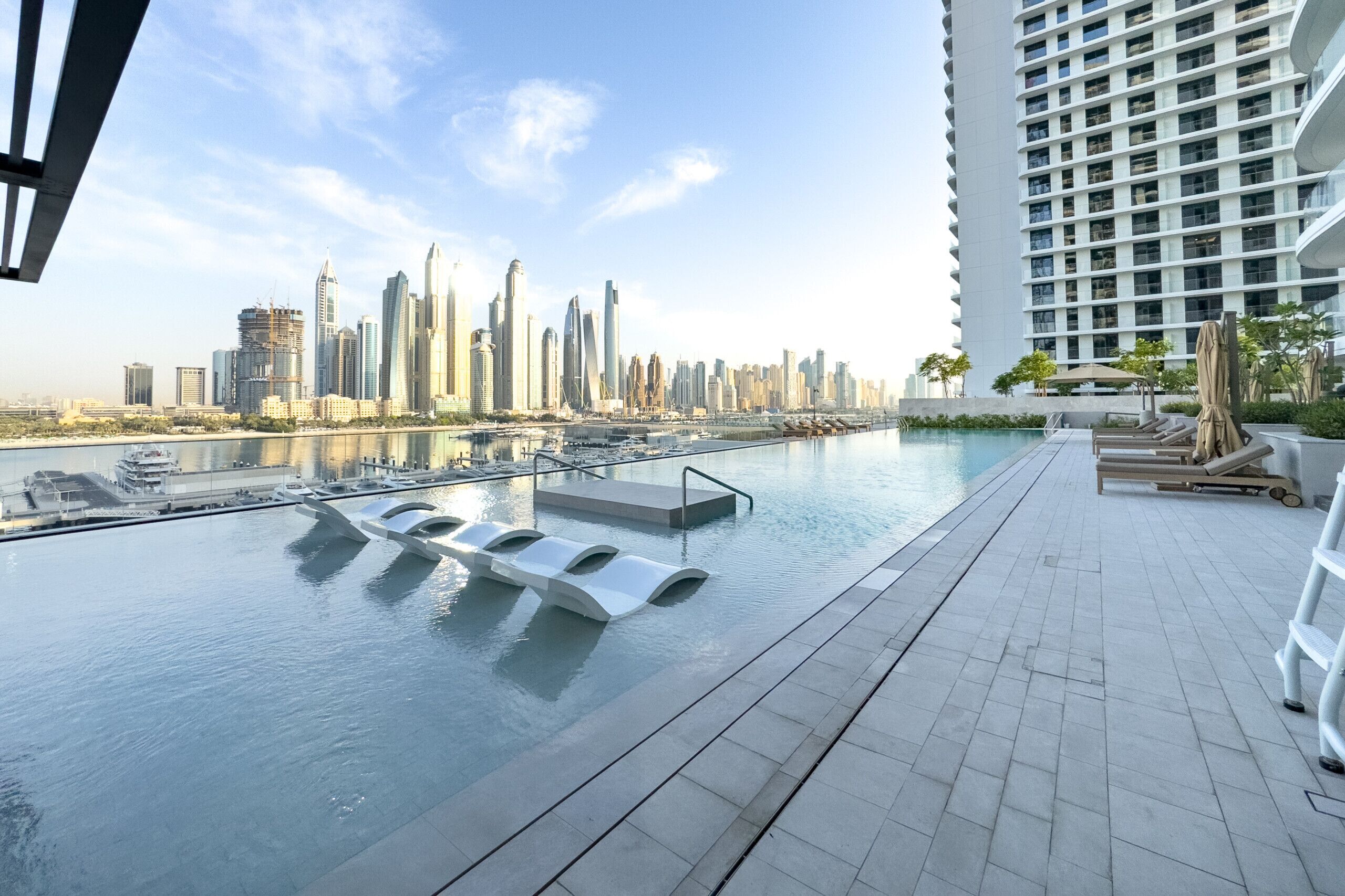 A rooftop pool with a city skyline view, modern architecture, and a calm water surface.