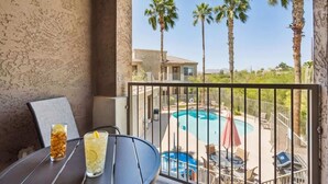 A balcony with a view of a swimming pool, palm trees, and a building in the background. - Panorama View - Mountain Views - Community Pool (Fountain Hills)