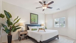 A bedroom with a bed, bedside tables, a ceiling fan, a window, and a potted plant. - Panorama View - Mountain Views - Community Pool (Fountain Hills)
