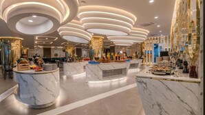 Un moderno vestíbulo de hotel con mostradores de mármol, luces de techo circulares y una zona de estar central.