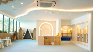 Club infantil con zona de juegos, mesas y mostrador de recepción.