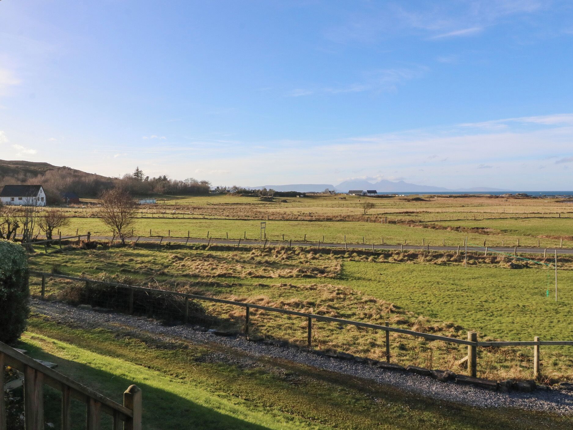 A rural landscape with fields, a fence, and a distant mountain range.